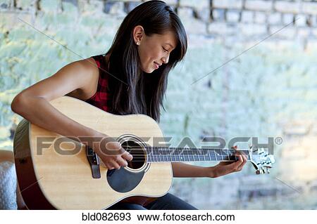 Asian girl strumming guitar View Large Photo Image Stock Image - Asian girl strumming guitar. Fotosearch