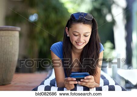 Stock Photograph - Asian girl text messaging on cell phone. Fotosearch