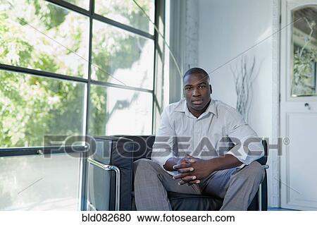 Black businessman sitting in armchair in office View Large Photo Image Stock Image - Black businessman sitting in armchair in office. Fotosearch
