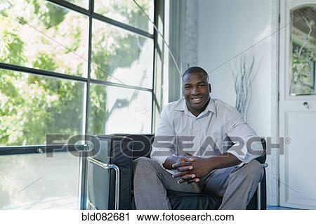 Black businessman sitting in armchair in office View Large Photo Image Stock Image - Black businessman sitting in armchair in office. Fotosearch