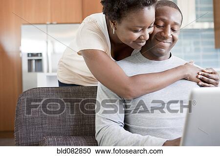 Black couple hugging and using laptop View Large Photo Image Stock Image - Black couple hugging and using laptop. Fotosearch