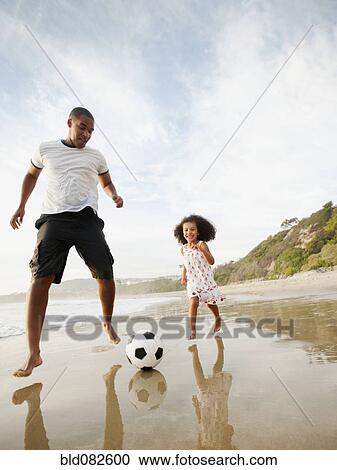 Black father kicking soccer ball with daughter on beach View Large Photo Image Stock Image - Black father kicking soccer ball with daughter on beach. Fotosearch