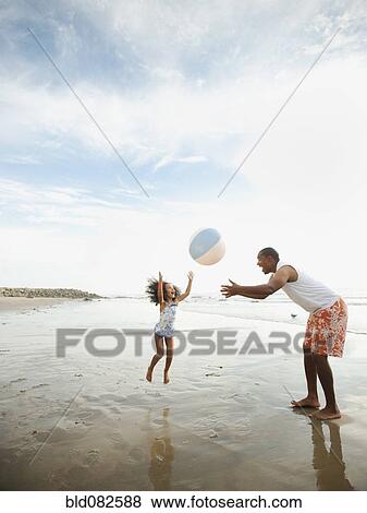 Black father throwing ball on beach with daughter View Large Photo Image Stock Photo - Black father throwing ball on beach with daughter. Fotosearch