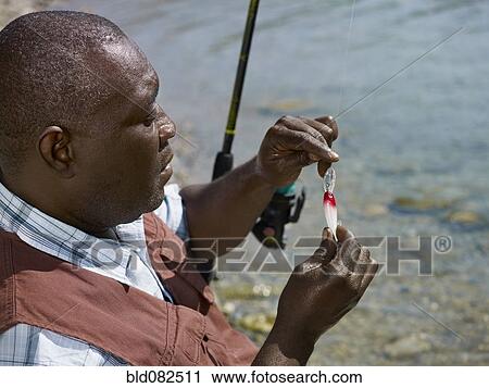 Black man putting lure on fishing pole View Large Photo Image Stock Image - Black man putting lure on fishing pole. Fotosearch