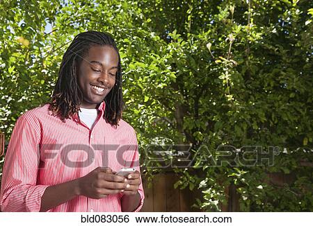 Black man text messaging on cell phone outdoors View Large Photo Image Stock Photograph - Black man text messaging on cell phone outdoors. Fotosearch