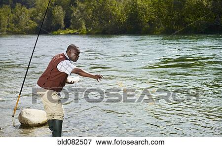 Stock Photo - Black man throwing chum into stream. Fotosearch