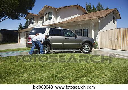 Stock Photo - Black man washing car in driveway. Fotosearch