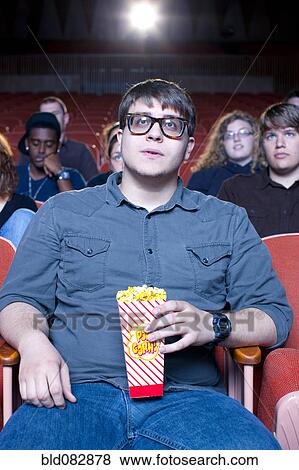 Caucasian man eating popcorn in movie theater View Large Photo Image Stock Photo - Caucasian man eating popcorn in movie theater. Fotosearch