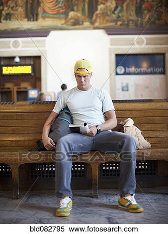 Stock Photography - Caucasian man reading book in train station. Fotosearch