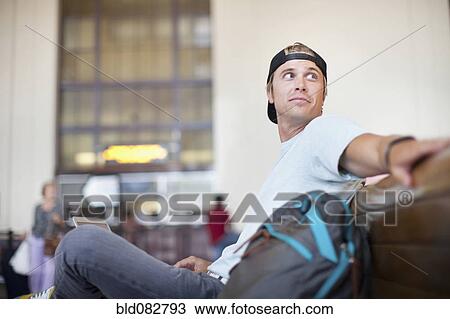 Stock Image - Caucasian man waiting in train station. Fotosearch