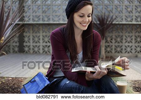 Stock Image - Caucasian woman reading book outdoors. Fotosearch