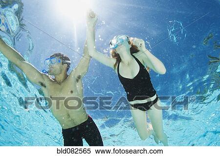 Stock Photography - Couple swimming in swimming pool. Fotosearch