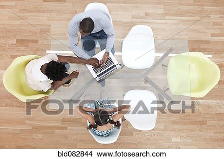 Picture - Family sitting at dining room table together. Fotosearch