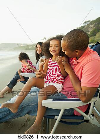 Stock Image - Family sitting together on beach. Fotosearch