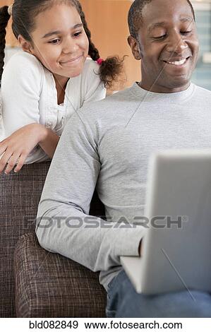 Stock Photo - Father and daughter using laptop together. Fotosearch