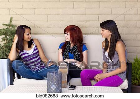 Friends sitting on sofa talking together View Large Photo Image Stock Photo - Friends sitting on sofa talking together. Fotosearch