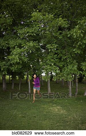 Stock Photo - Hispanic woman running through park. Fotosearch