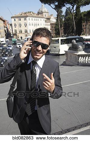 Stock Image - Italian businessman talking on cell phone outdoors. Fotosearch