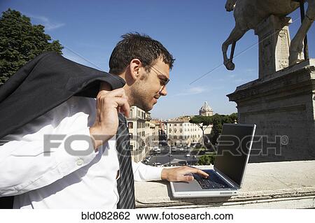 Italian businessman using laptop outdoors View Large Photo Image Stock Image - Italian businessman using laptop outdoors. Fotosearch