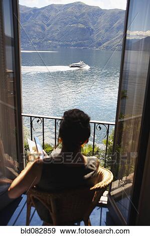 Stock Photo - Italian woman sitting balcony looking at lake. Fotosearch