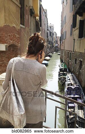 Stock Photography - Italian woman talking on cell phone near canal. Fotosearch