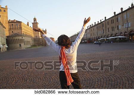 Stock Photograph - Italian woman with arms raised in piazza. Fotosearch
