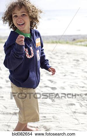 Picture - Mixed race boy playing on beach. Fotosearch
