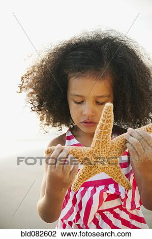 Mixed race girl holding starfish on beach View Large Photo Image Stock Image - Mixed race girl holding starfish on beach. Fotosearch