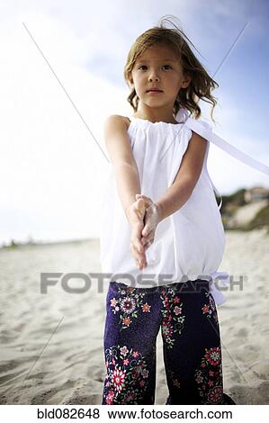 Stock Photo - Mixed race girl playing on beach. Fotosearch