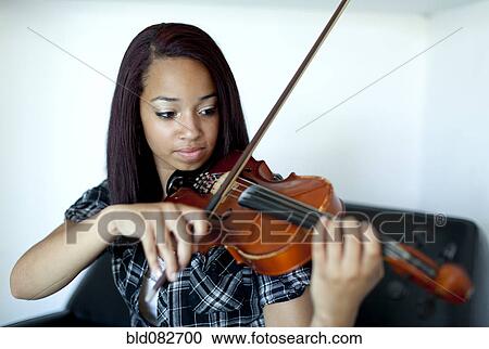 Stock Image - Mixed race girl practicing violin. Fotosearch