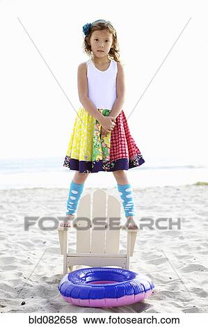 Mixed race girl standing on chair on beach View Large Photo Image Stock Photo - Mixed race girl standing on chair on beach. Fotosearch