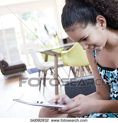 Mixed race girl using digital tablet in living room View Large Photo Image Stock Image - Mixed race girl using digital tablet in living room. Fotosearch