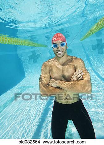 Picture - Mixed race man standing underwater in swimming pool. Fotosearch