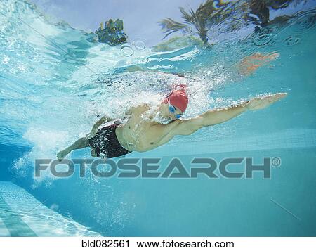 Stock Image - Mixed race man swimming in swimming pool. Fotosearch