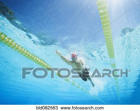 Stock Image - Mixed race man swimming in swimming pool. Fotosearch
