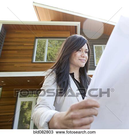 Mixed race real estate agent standing near house reviewing blueprints View Large Photo Image Stock Image - Mixed race real estate agent standing near house reviewing blueprints. Fotosearch