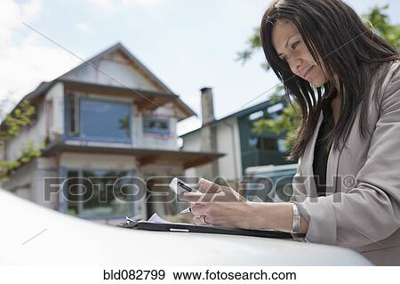 Stock Photo - Mixed race real estate agent standing near house under construction. Fotosearch