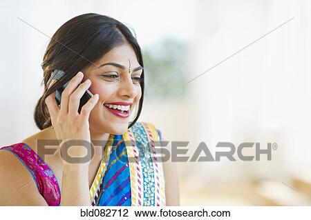 Stock Image - Mixed race woman in traditional Indian clothing talking on cell phone. Fotosearch