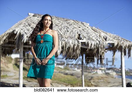 Stock Image - Mixed race woman standing near tropical hut. Fotosearch