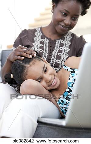 Stock Image - Mother and daughter using laptop together. Fotosearch