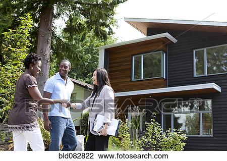 Real estate agent greeting couple at house View Large Photo Image Stock Image - Real estate agent greeting couple at house. Fotosearch