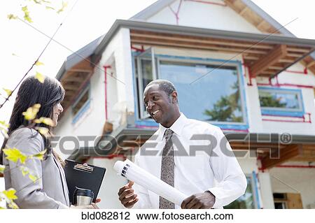 Stock Image - Real estate agents near house under construction. Fotosearch