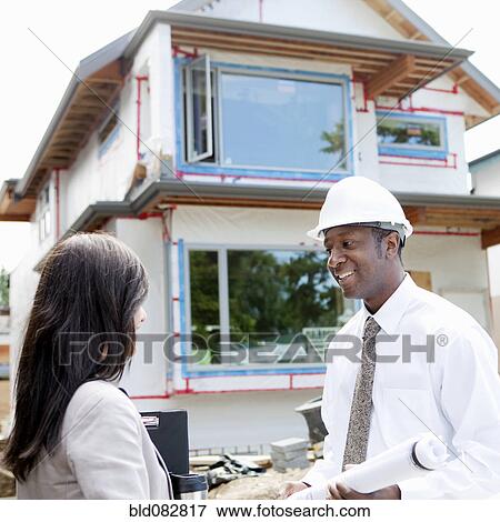 Real estate agents near house under construction View Large Photo Image Stock Photo - Real estate agents near house under construction. Fotosearch