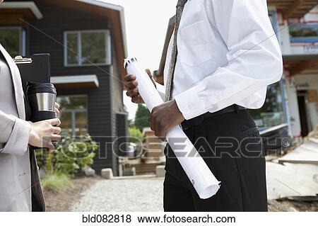 Real estate agents near house under construction View Large Photo Image Stock Photo - Real estate agents near house under construction. Fotosearch