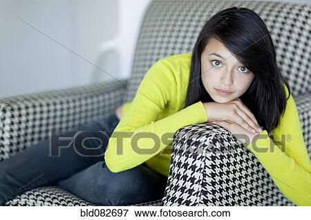 Stock Photo - Serious Asian girl sitting in armchair. Fotosearch