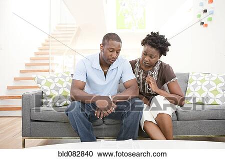 Serious couple sitting on sofa together View Large Photo Image Stock Image - Serious couple sitting on sofa together. Fotosearch