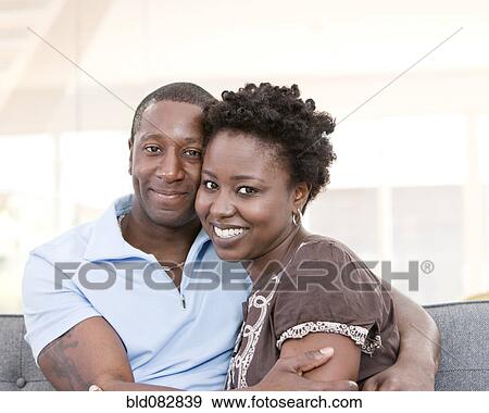 Stock Photo - Smiling couple sitting on sofa together. Fotosearch
