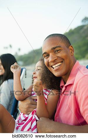 Smiling father holding daughter on beach View Large Photo Image Stock Image - Smiling father holding daughter on beach. Fotosearch