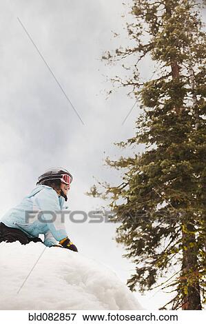 Stock Photo - Smiling girl kneeling in snow. Fotosearch