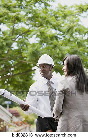 Woman talking to architect holding blueprints View Large Photo Image Stock Image - Woman talking to architect holding blueprints. Fotosearch